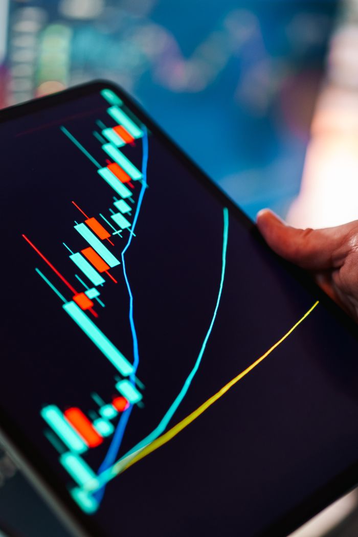 services-03 A close-up of a tablet displaying a colorful candlestick chart, ideal for finance and technology themes.